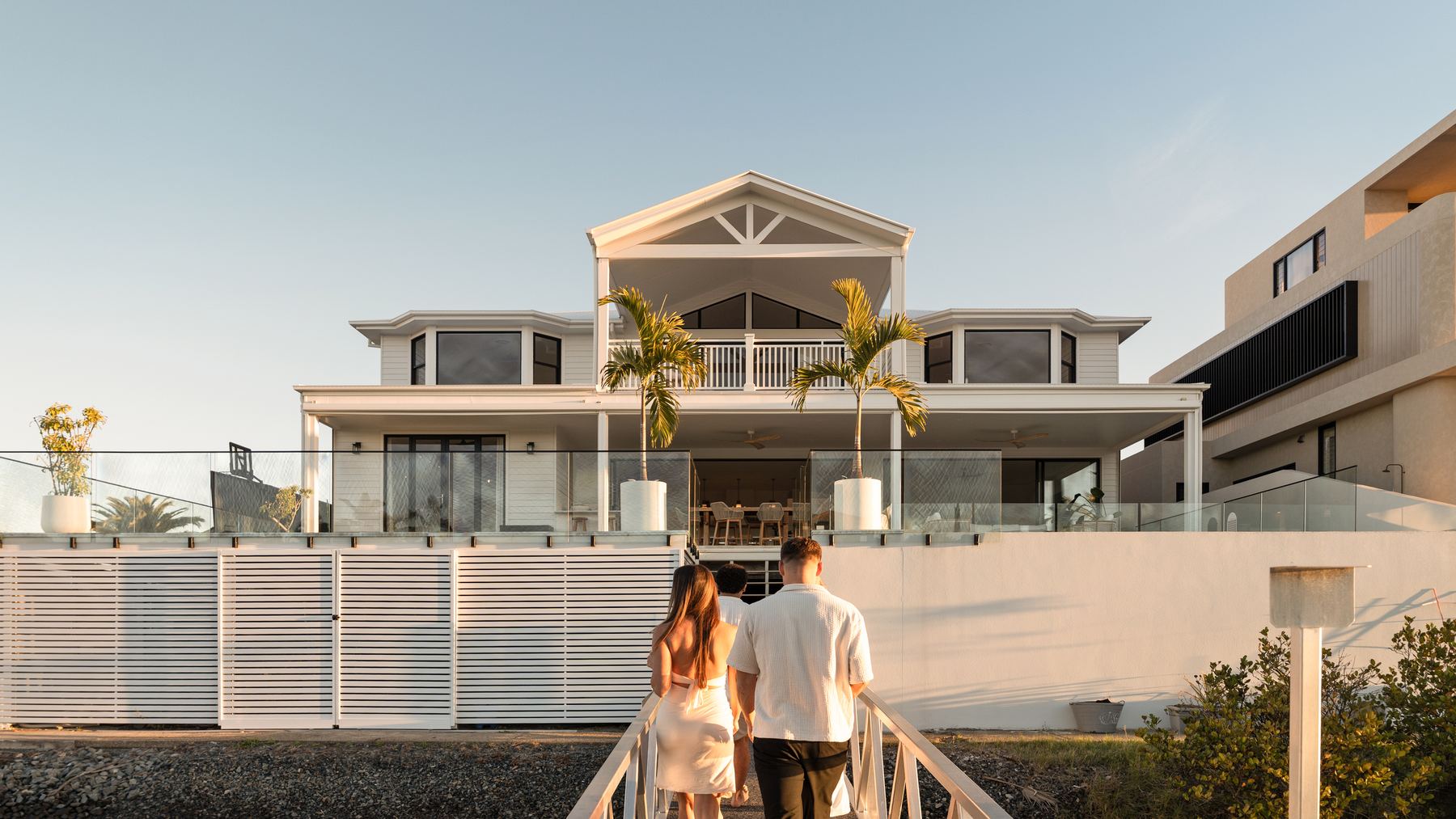 A couple walking up to a beachfront residence on the Gold Coast at golden hour